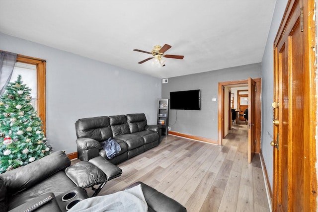 living room featuring baseboards, ceiling fan, and light wood finished floors