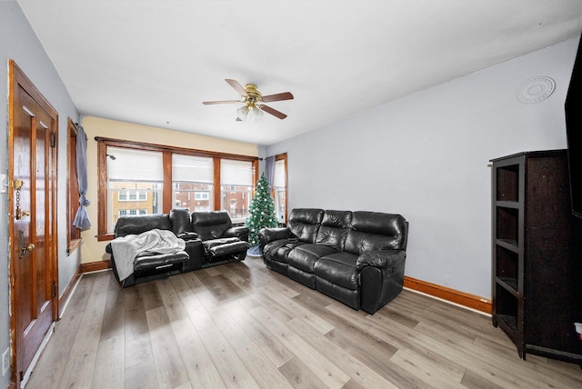 living room with light wood-style floors, baseboards, and a ceiling fan