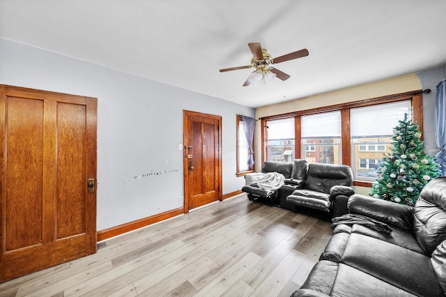 living room with a ceiling fan, light wood-style flooring, and baseboards