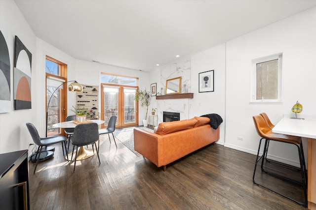 living area featuring a fireplace, baseboards, and dark wood finished floors