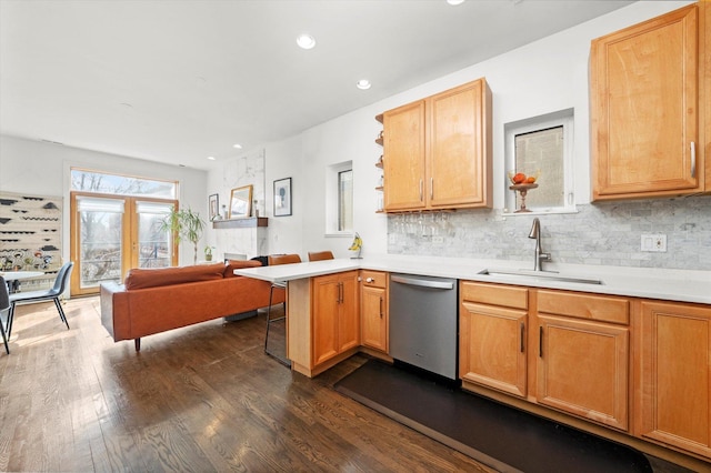 kitchen featuring open floor plan, a kitchen breakfast bar, a peninsula, stainless steel dishwasher, and a sink