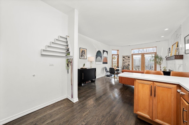 kitchen featuring brown cabinets, light countertops, dark wood finished floors, and baseboards