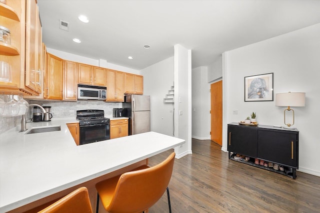 kitchen featuring tasteful backsplash, visible vents, a peninsula, stainless steel appliances, and a sink