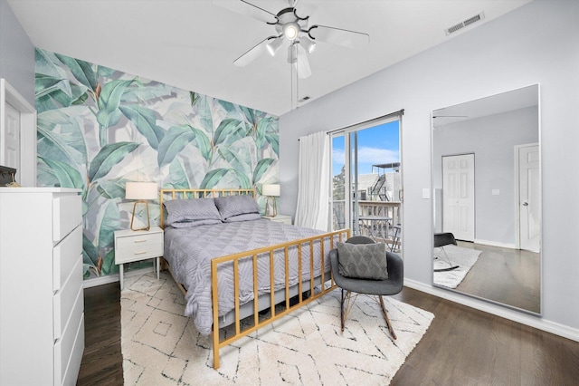 bedroom with an accent wall, wood finished floors, visible vents, baseboards, and wallpapered walls