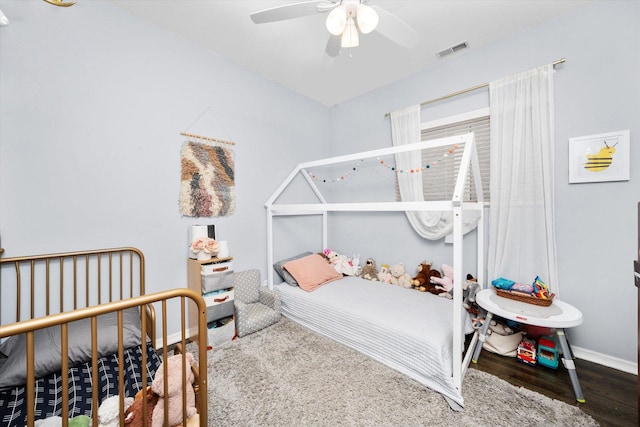 bedroom featuring a ceiling fan, wood finished floors, visible vents, and baseboards