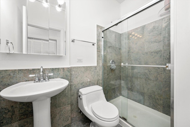 bathroom featuring a wainscoted wall, a stall shower, toilet, and tile walls