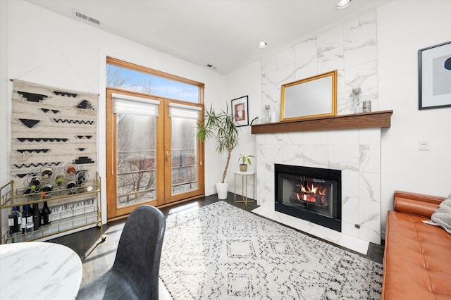 living room featuring a premium fireplace, visible vents, and recessed lighting