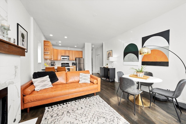 living room featuring baseboards, dark wood-type flooring, a fireplace, and recessed lighting