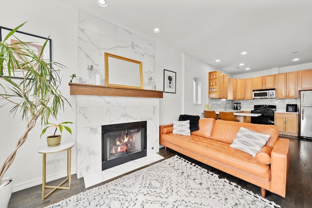 living room featuring a tile fireplace, wood finished floors, baseboards, and recessed lighting