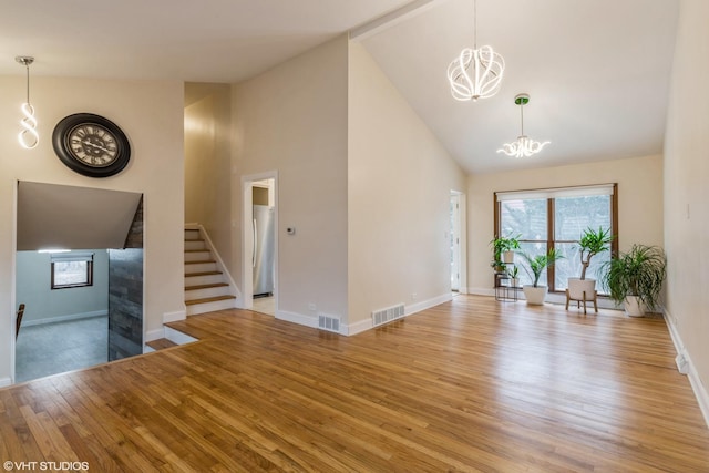 unfurnished living room featuring light wood-type flooring, stairs, visible vents, and a chandelier