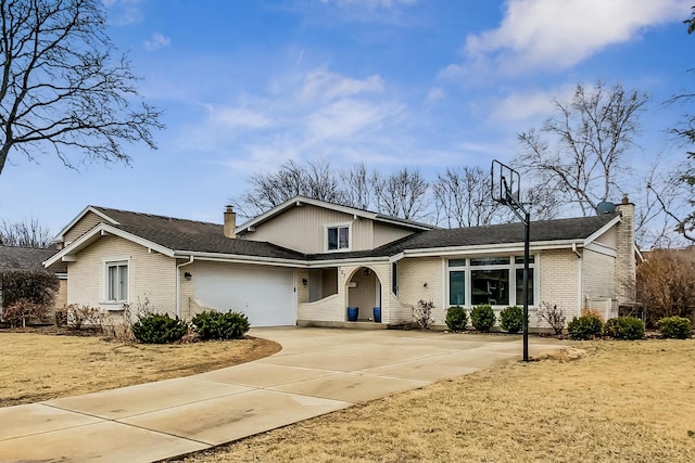 split level home featuring a garage, a chimney, concrete driveway, and brick siding