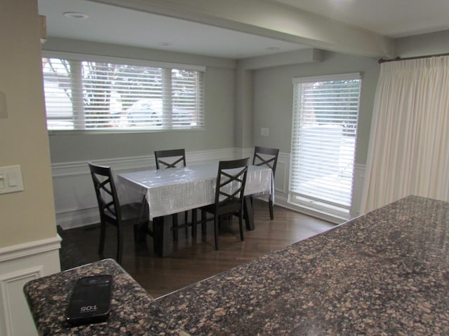 dining area featuring a wainscoted wall, a decorative wall, and wood finished floors