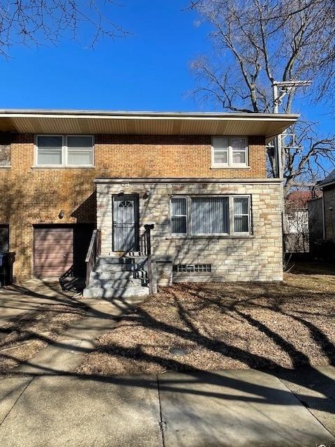 view of front facade featuring stone siding, an attached garage, and concrete driveway