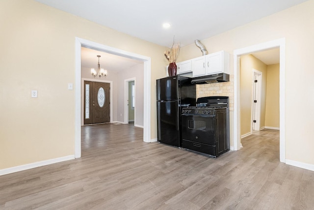 kitchen with under cabinet range hood, baseboards, white cabinets, light wood-type flooring, and black appliances