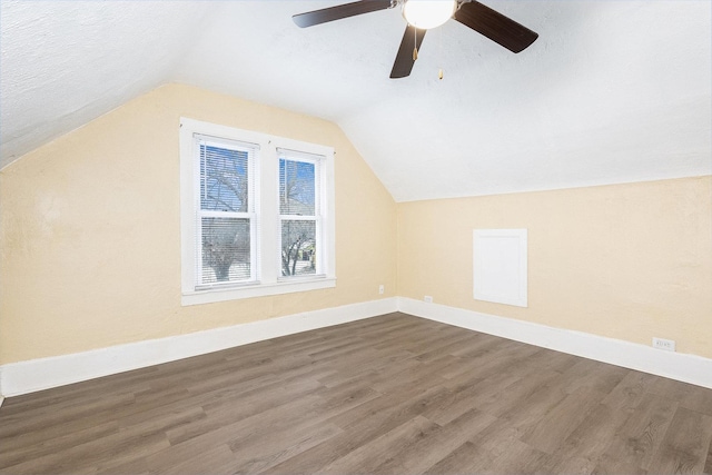 bonus room featuring dark wood-style floors, baseboards, vaulted ceiling, and a textured ceiling