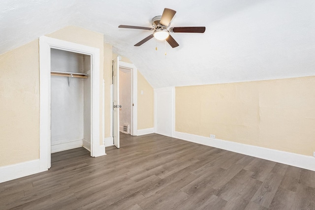 unfurnished bedroom featuring lofted ceiling, a closet, wood finished floors, and baseboards