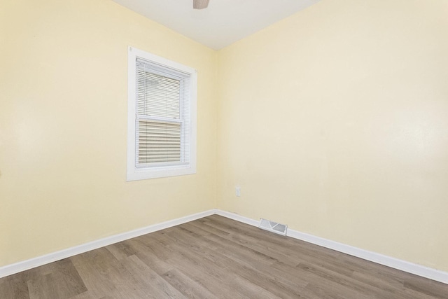 empty room with dark wood-type flooring, visible vents, ceiling fan, and baseboards