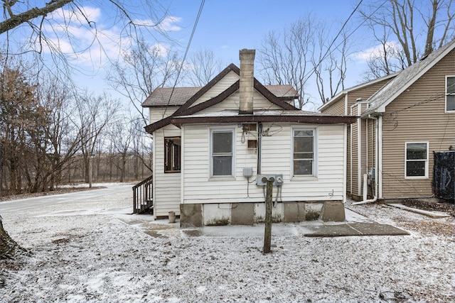 snow covered house featuring crawl space and a chimney