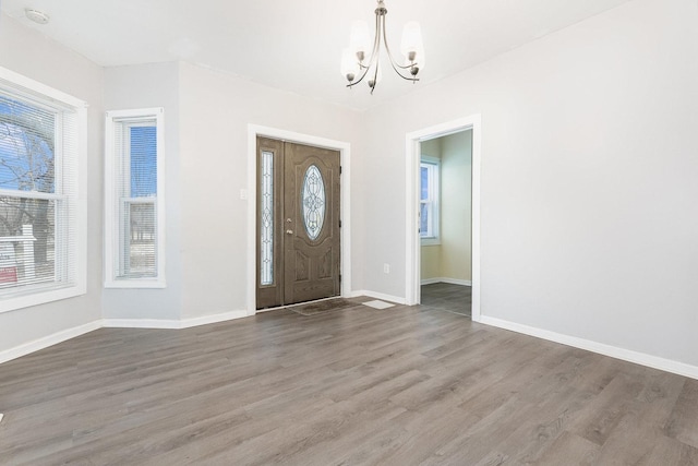 foyer entrance with a chandelier, baseboards, wood finished floors, and a healthy amount of sunlight