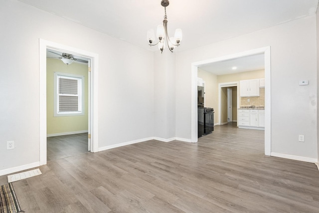 unfurnished dining area featuring an inviting chandelier, wood finished floors, and baseboards