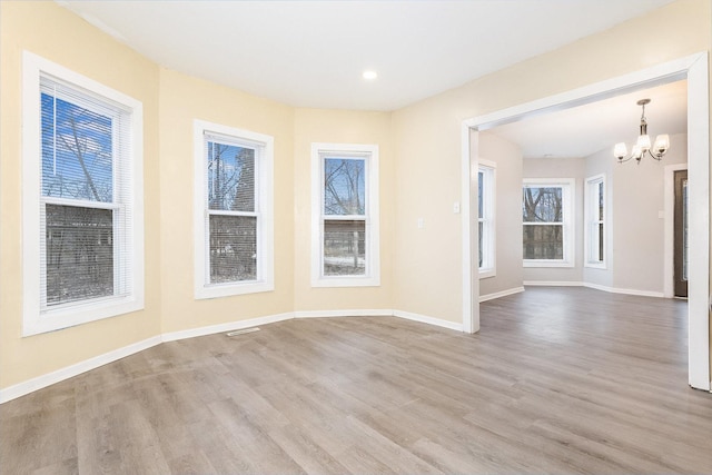 unfurnished room with a chandelier, wood finished floors, and baseboards