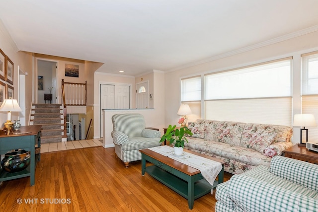 living area featuring wood finished floors, stairs, and ornamental molding