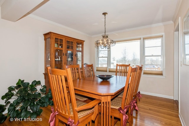 dining space with light wood finished floors, a notable chandelier, and crown molding