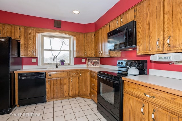 kitchen featuring black appliances, brown cabinetry, and light countertops