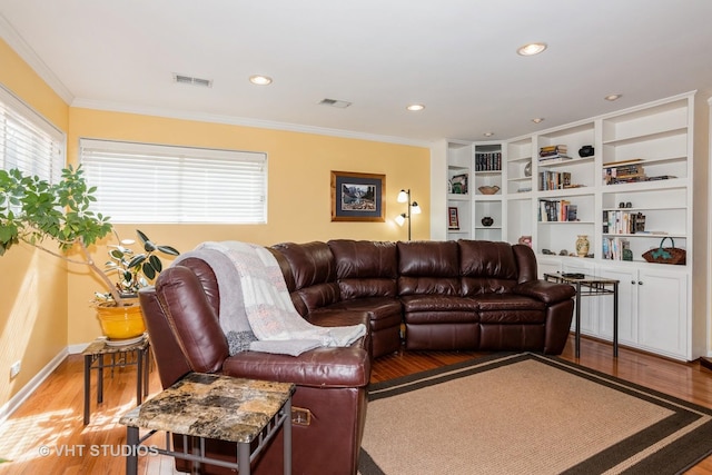 living area with a wealth of natural light, visible vents, wood finished floors, and ornamental molding