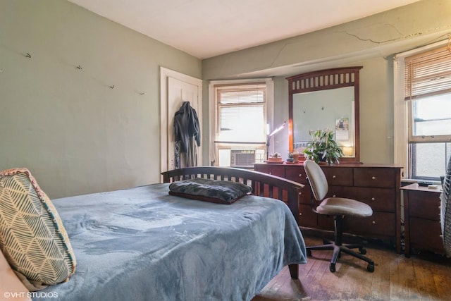 bedroom with hardwood / wood-style flooring, multiple windows, and cooling unit