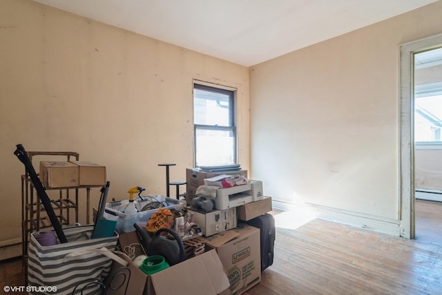 misc room with a baseboard radiator, wood-type flooring, and a wealth of natural light