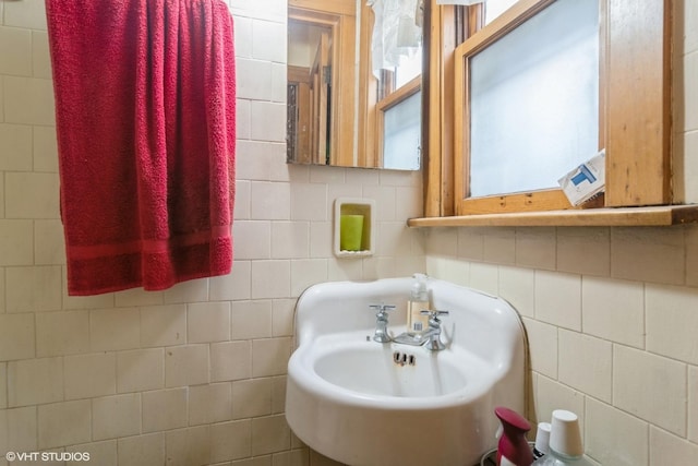 bathroom with tasteful backsplash, a sink, and tile walls