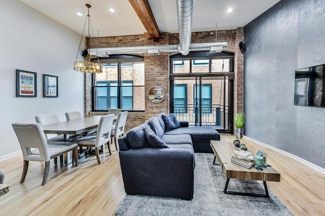 living area featuring brick wall, wood finished floors, and a towering ceiling