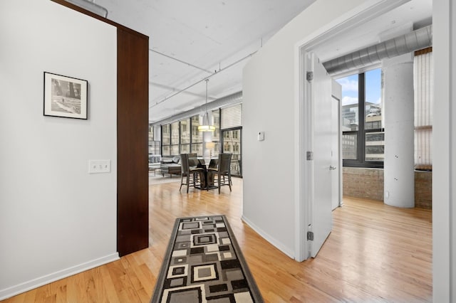 corridor featuring light wood-style floors and baseboards