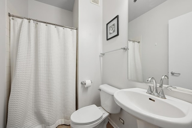 full bathroom with toilet, curtained shower, visible vents, and a sink