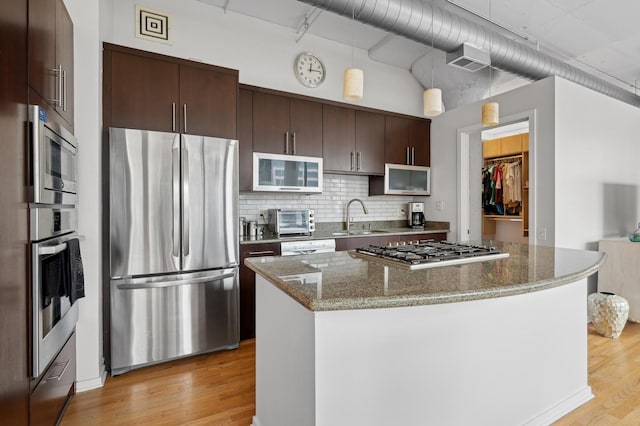 kitchen featuring a center island, light wood-style flooring, appliances with stainless steel finishes, a sink, and dark brown cabinetry