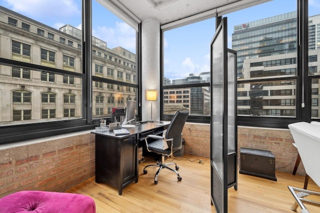 office featuring a city view, brick wall, and wood finished floors