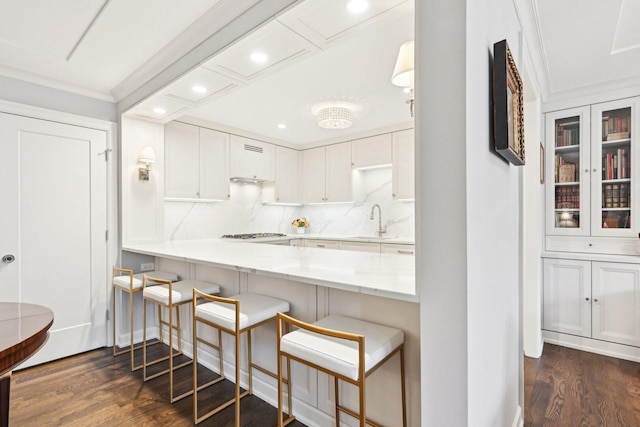 kitchen featuring ornamental molding, dark wood-type flooring, a sink, and white cabinetry