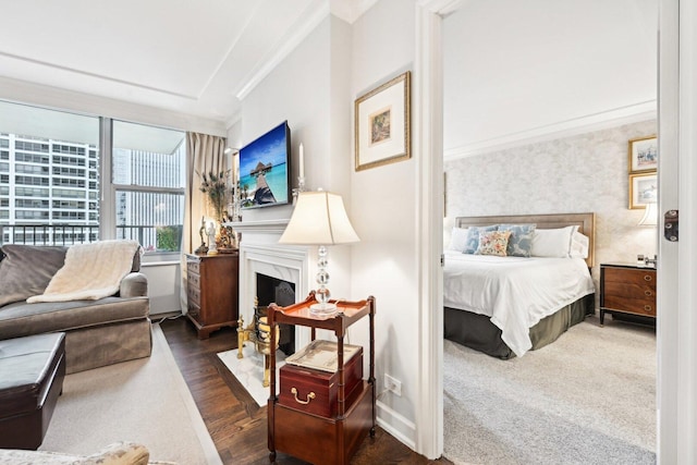 bedroom featuring crown molding, a fireplace, baseboards, and wood finished floors