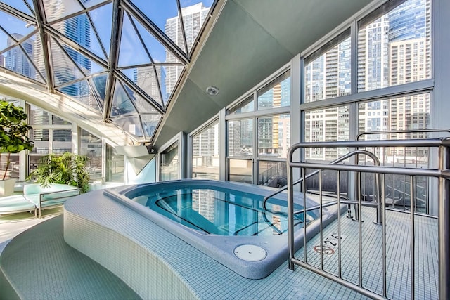 view of swimming pool featuring glass enclosure and a jacuzzi