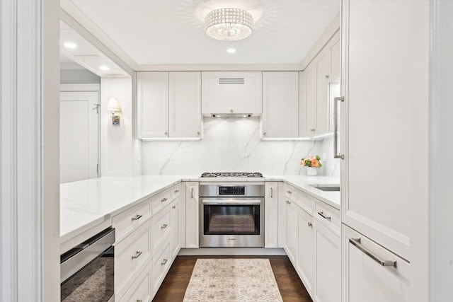 kitchen with tasteful backsplash, stainless steel oven, light stone countertops, gas stovetop, and white cabinetry