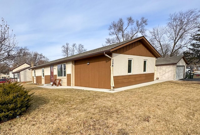 view of property exterior featuring a garage, a lawn, and an outbuilding