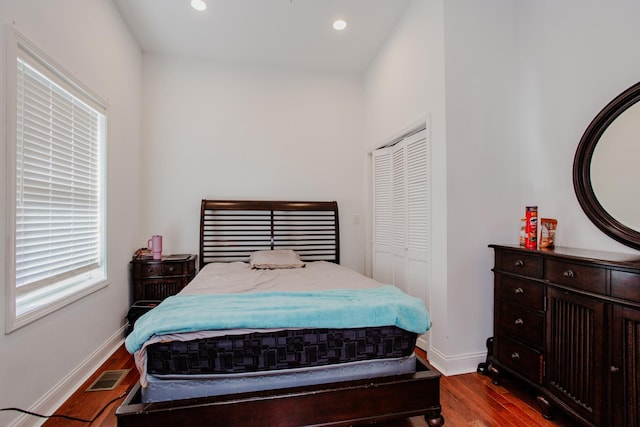 bedroom with recessed lighting, wood finished floors, visible vents, baseboards, and a closet