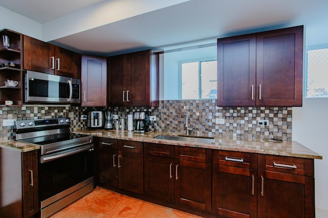 kitchen featuring decorative backsplash, appliances with stainless steel finishes, light stone countertops, open shelves, and a sink