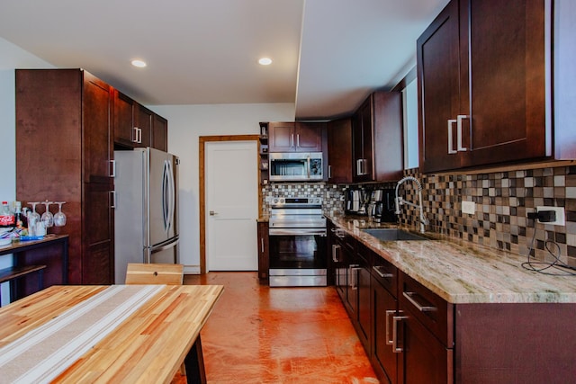 kitchen featuring dark brown cabinetry, tasteful backsplash, appliances with stainless steel finishes, light stone countertops, and a sink