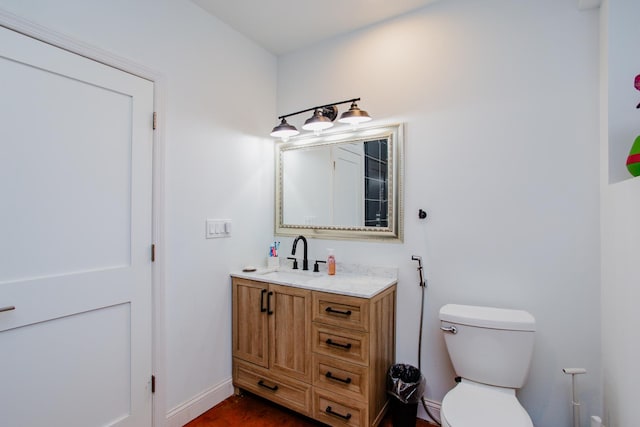 bathroom featuring toilet, baseboards, and vanity