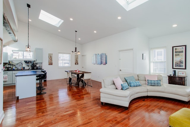 living area featuring a skylight, high vaulted ceiling, wood finished floors, and recessed lighting