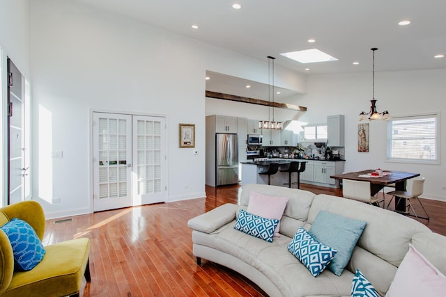 living area featuring a towering ceiling, baseboards, visible vents, and wood finished floors