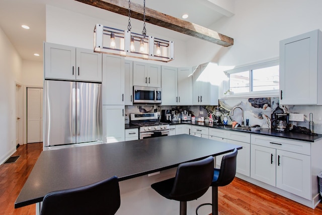 kitchen with tasteful backsplash, visible vents, dark countertops, appliances with stainless steel finishes, and a sink