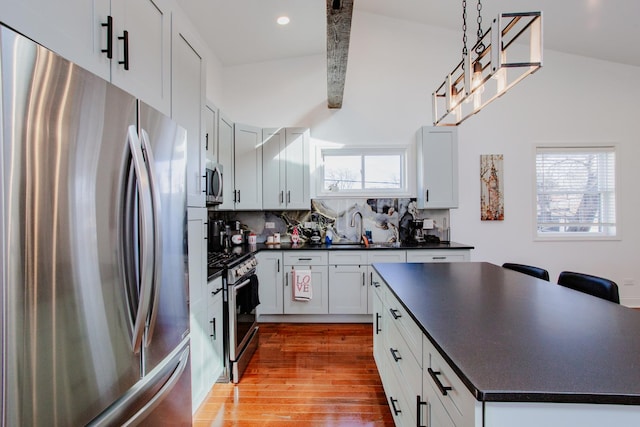 kitchen with dark countertops, light wood-type flooring, appliances with stainless steel finishes, and a sink